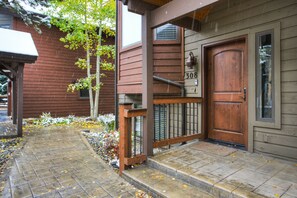 A wooden house with a number '308' on the door, a porch with a railing, and a stone pathway. - Village Point 308 (Breckenridge)