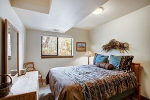 A bedroom with a large bed, a window with a view of trees, a lamp, and a picture on the wall. - Village Point 308 (Breckenridge)