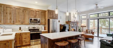 A modern kitchen with wooden cabinets, stainless steel appliances, and a large island with bar stools.