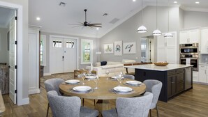 A spacious kitchen with modern appliances, a dining area with a round table, and a ceiling fan. - Crain's Perch will Wow you! (Fort Myers Beach)