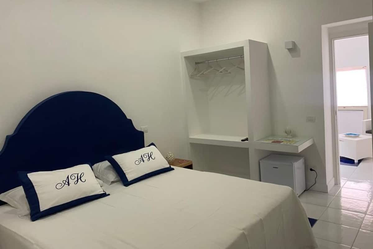 Ein Schlafzimmer mit einem Bett, einem Kleiderschrank, einem Schreibtisch und einer kleinen Kommode.