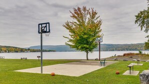 Ein Park mit einem Basketballplatz, Picknicktischen und Blick auf einen See.