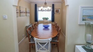 Un comedor con una mesa de madera, sillas, una araña y obras de arte en las paredes.