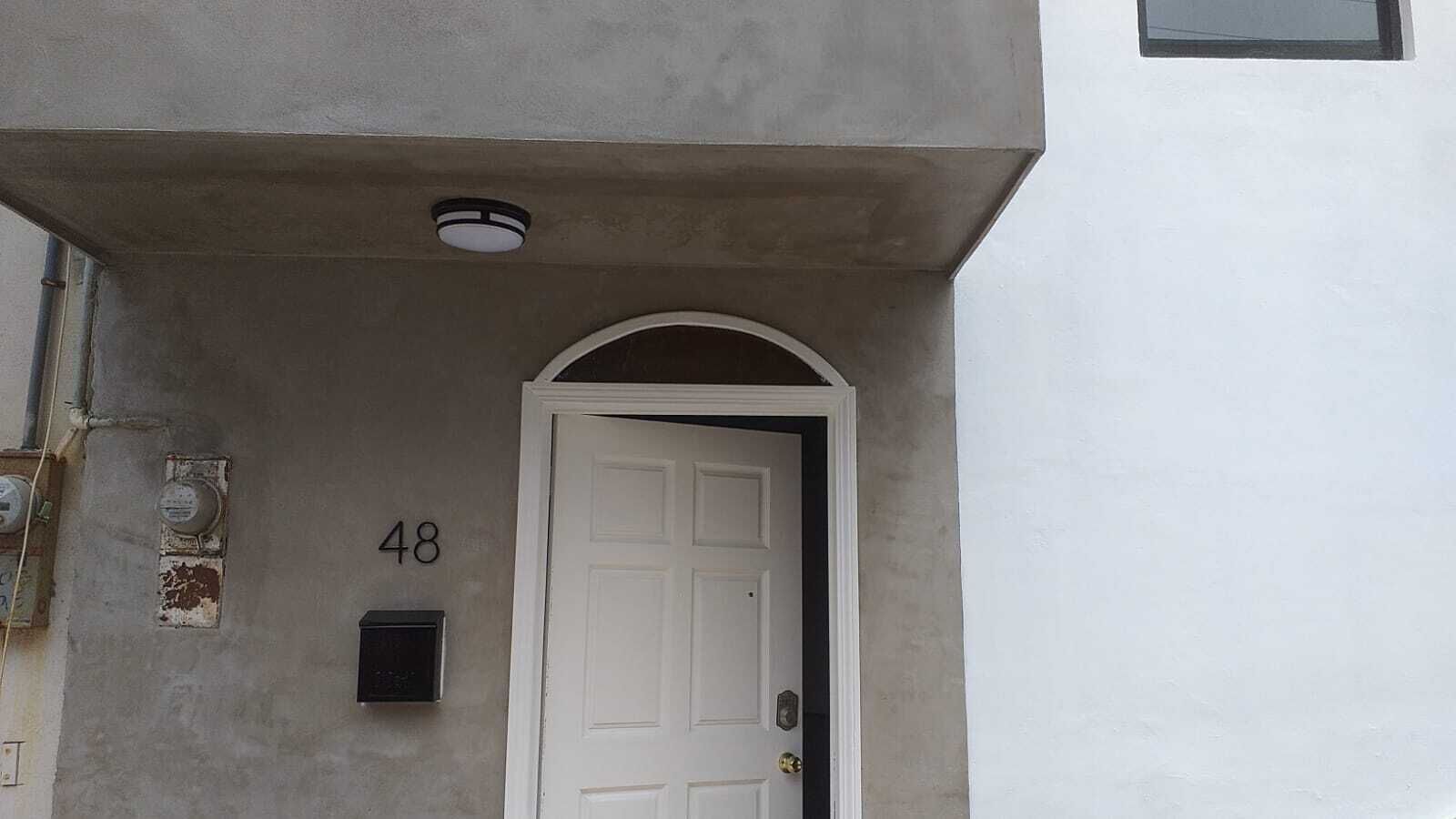 A building entrance with a white door, the number 48, and a small black mailbox.