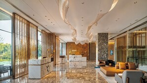A modern lobby with a marble floor, a reception desk, a seating area with sofas, and large windows. - Radisson Hotel, Beijing Daxing Airport (Daxing)