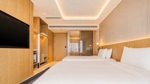 A modern hotel room with a large bed, a flat-screen TV, a wardrobe, and a bathroom visible through a glass door. - Radisson Hotel, Beijing Daxing Airport     (Daxing)