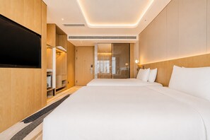 A modern hotel room with a large bed, a flat-screen TV, a wardrobe, and a bathroom visible through a glass door. - Radisson Hotel, Beijing Daxing Airport     (Daxing)