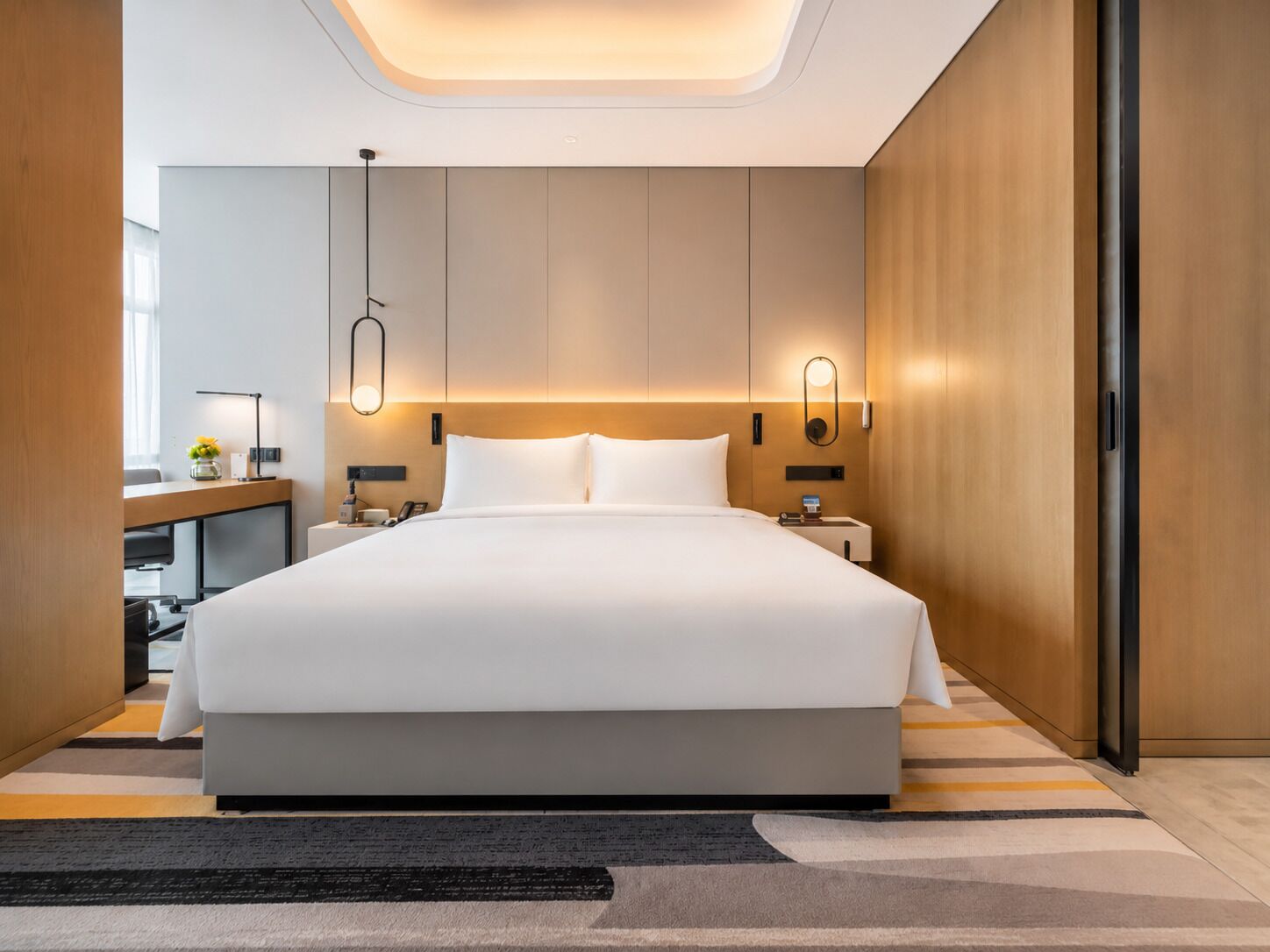 Une chambre d’hôtel moderne avec un grand lit, des tables de chevet, un bureau et une chaise.