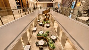 A multi-level indoor space with seating areas, plants, and a glass railing. - Radisson Hotel, Beijing Daxing Airport     (Daxing)