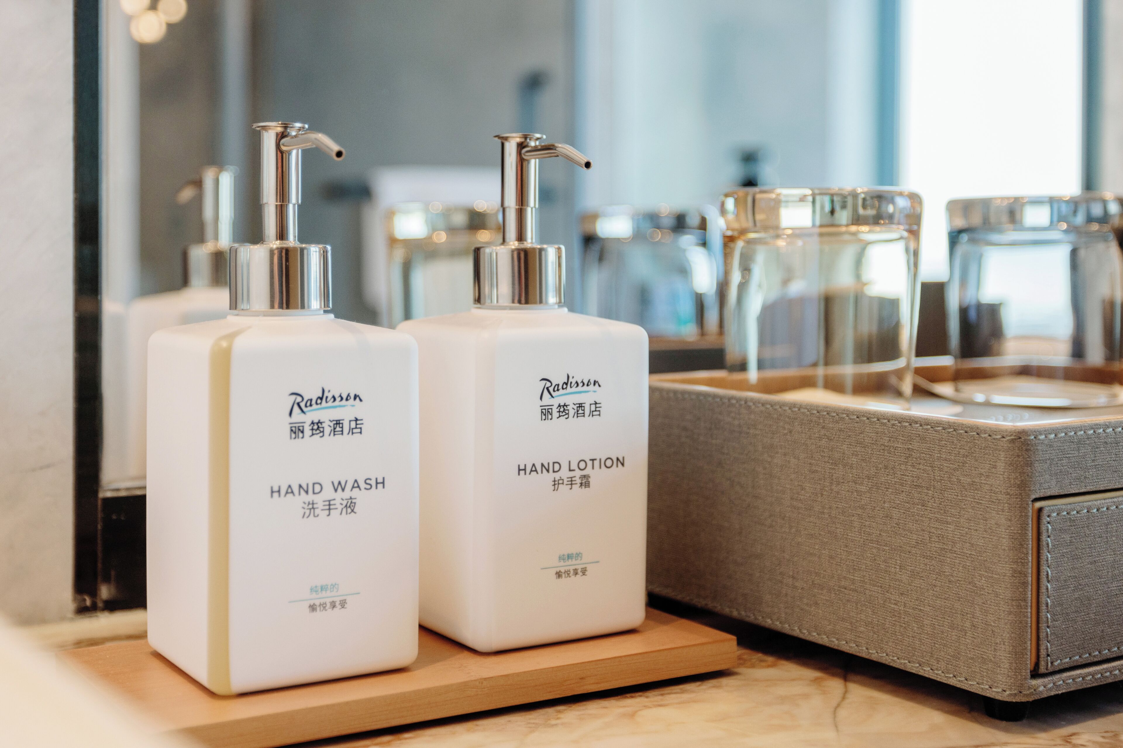 Two bottles of Radisson hand wash and lotion on a wooden tray.