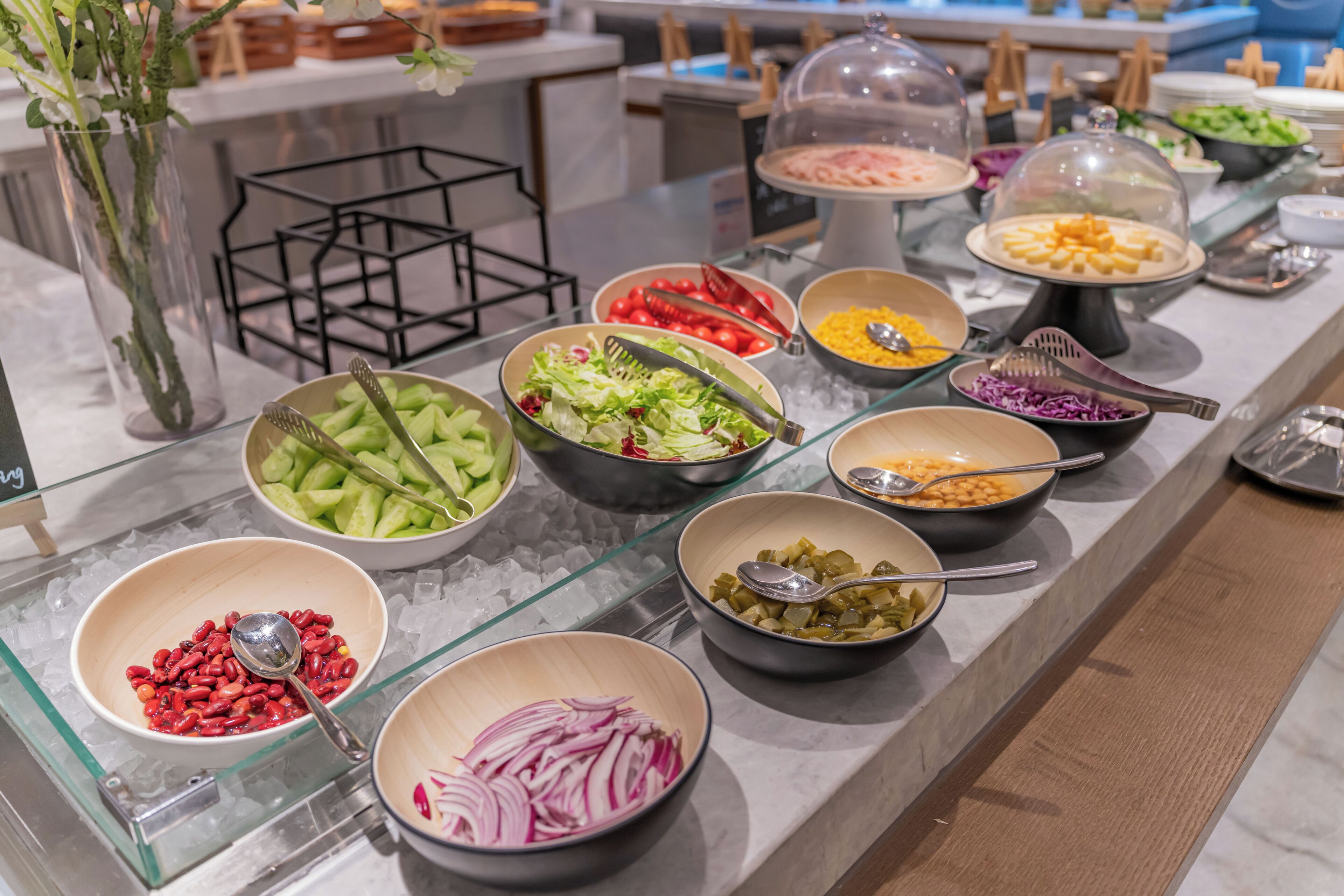 A buffet with various food items including salads, vegetables, and beans.