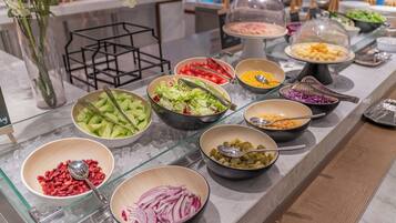 A buffet with various food items including salads, vegetables, and beans.