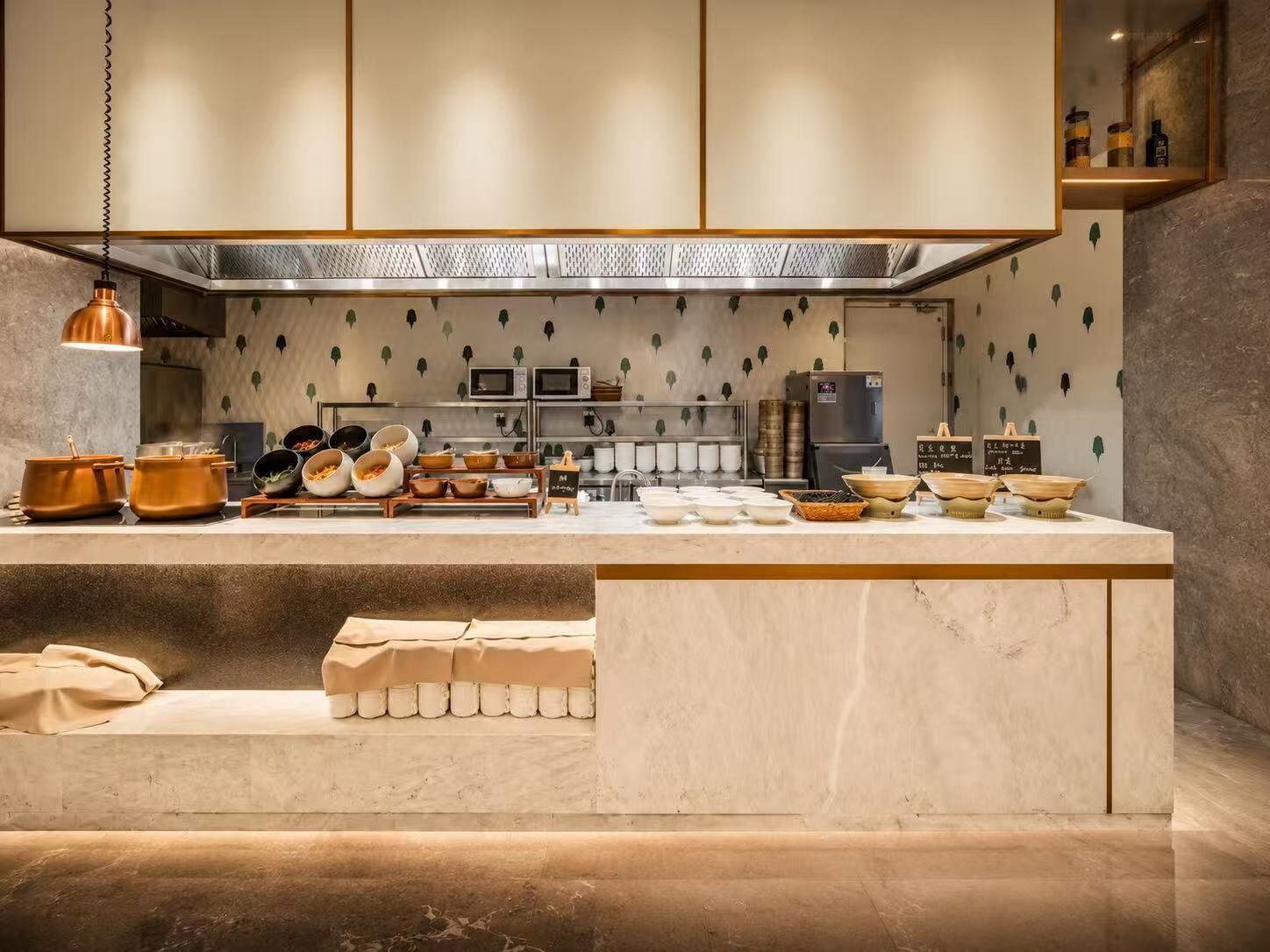 Una cocina moderna con encimera de mármol, electrodomésticos de acero inoxidable y un diseño de hojas decorativas en la pared.