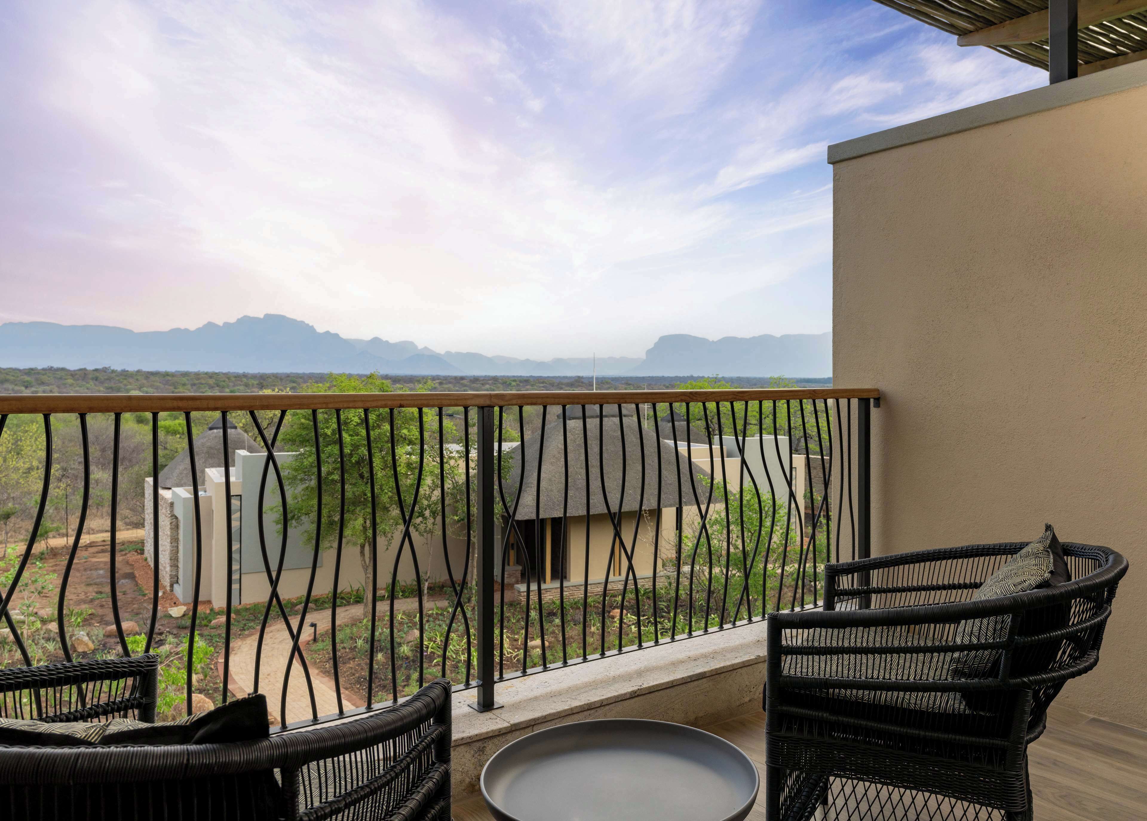Ein Balkon mit Korbmöbeln und Blick auf ferne Berge.