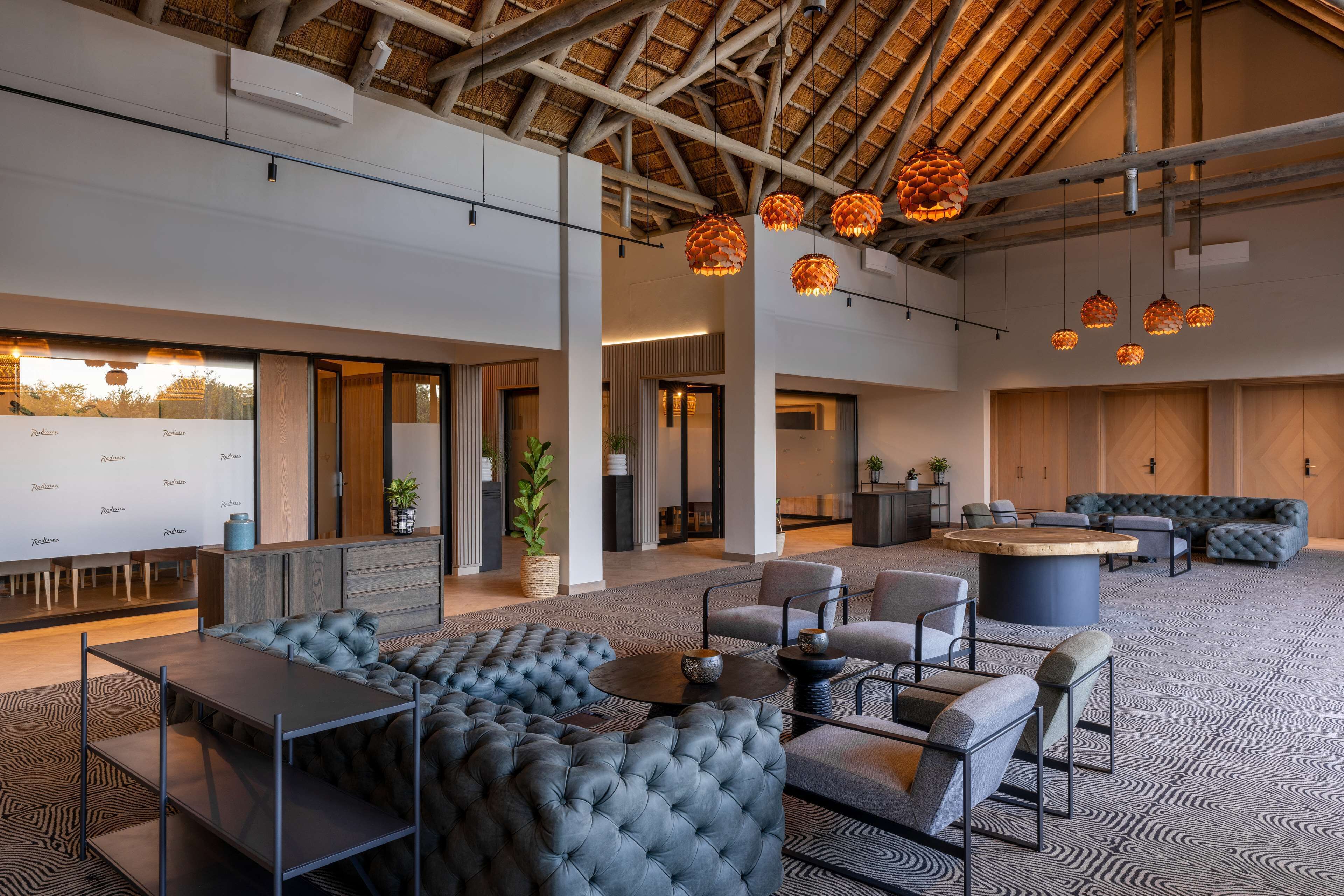 A spacious lounge area with a high ceiling, modern furniture, and hanging pendant lights.