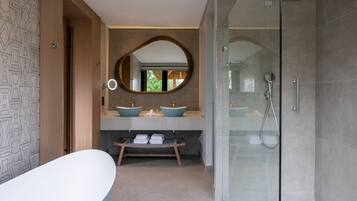 A modern bathroom with a freestanding bathtub, two vessel sinks, a large mirror, and a glass-enclosed shower area.