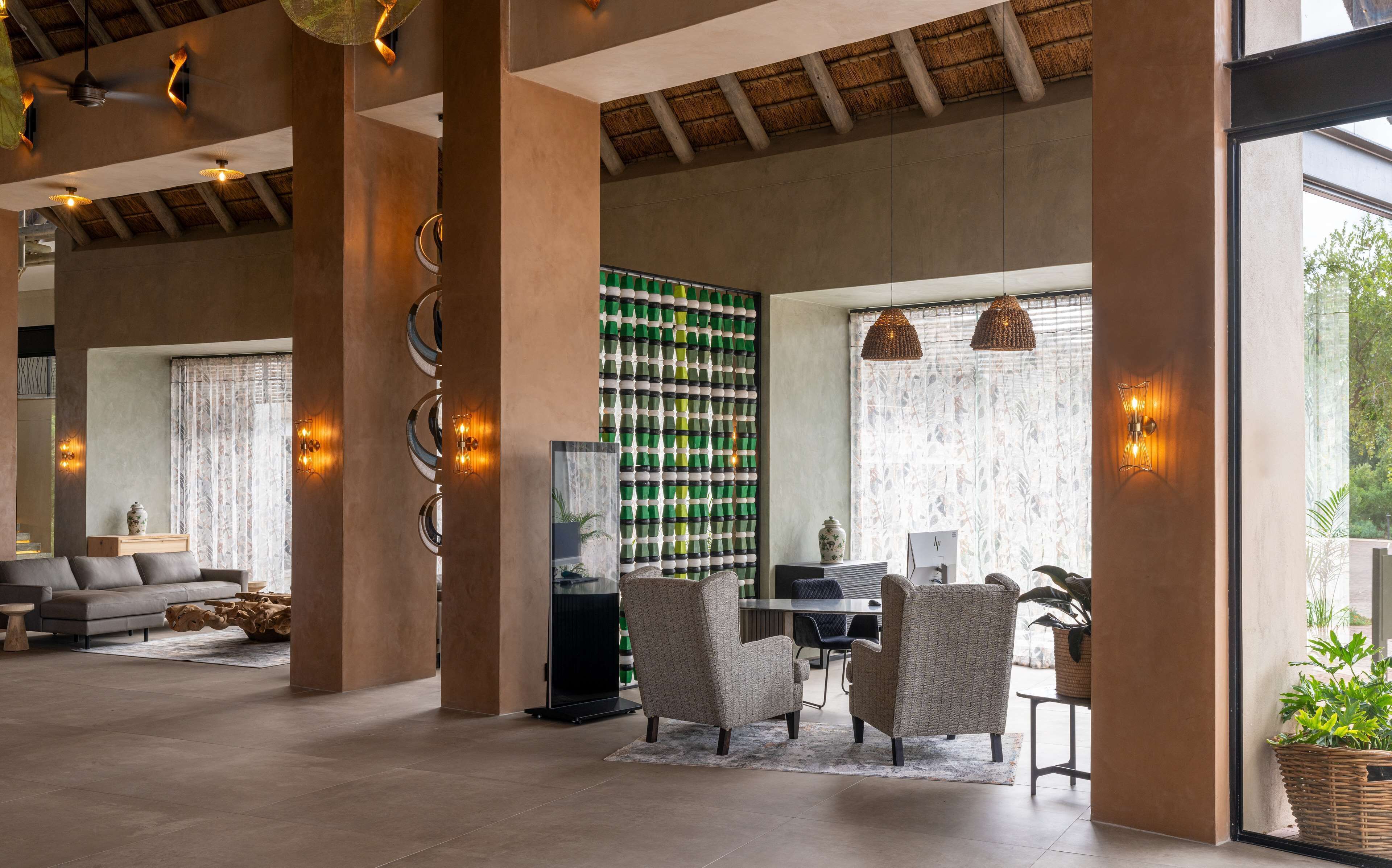 A spacious living area with high ceilings, a dining area with wicker chairs, and a wall decorated with green bottles.