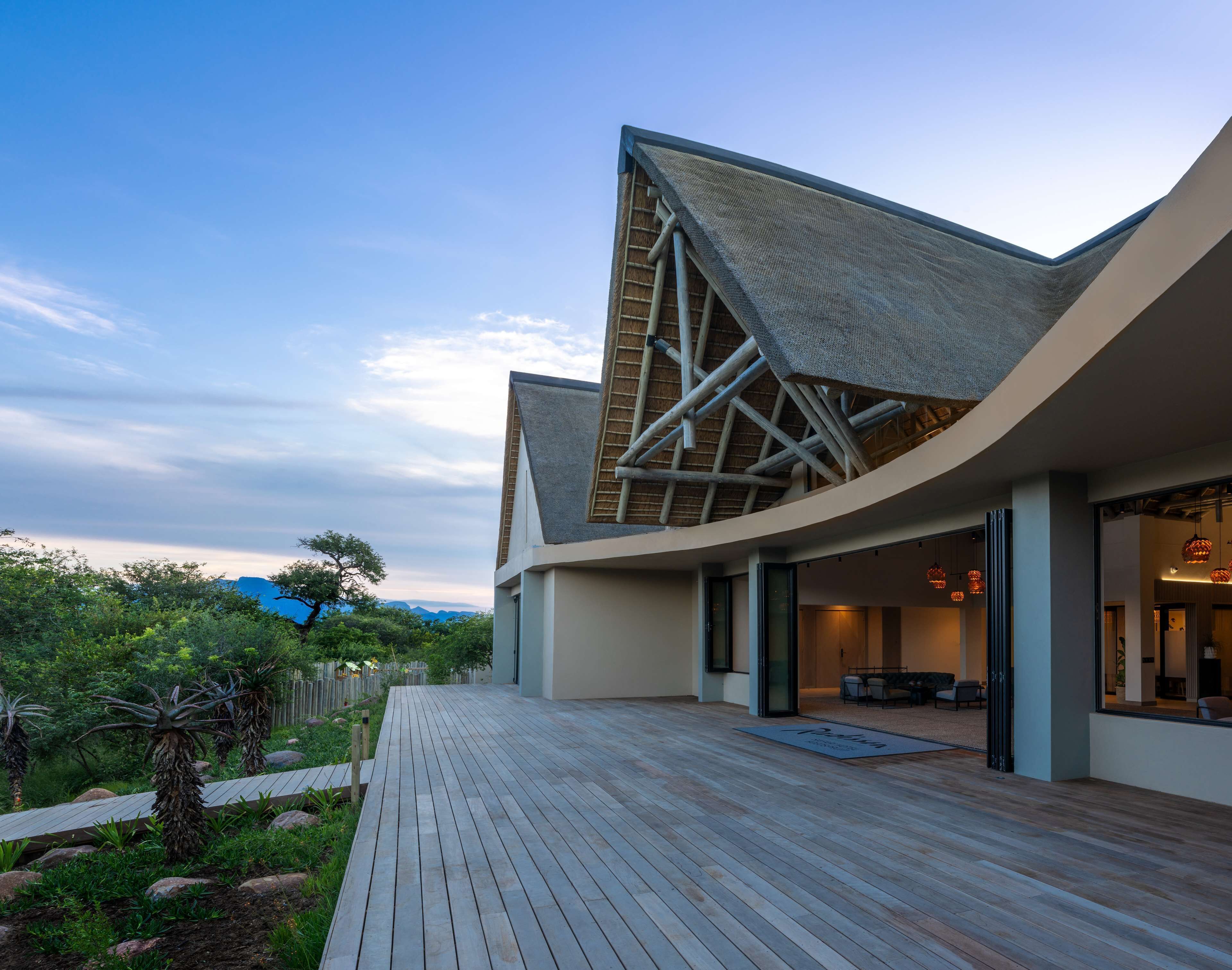 A modern building with a unique triangular roof structure, a wooden deck, and a view of the surrounding landscape.