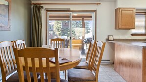 A dining area with a round table and wooden chairs, a kitchen counter, and a sliding glass door leading to an outdoor area.
