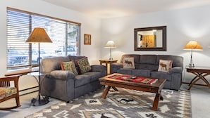 A living room with two grey sofas, a wooden coffee table, and a patterned rug.