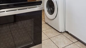 A kitchen with a microwave, oven, and stacked washer and dryer.