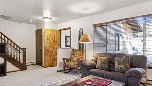 A living room with a sofa, a coffee table, a rocking chair, and a lamp.