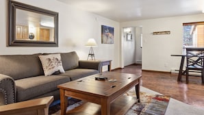 A living room with a sofa, coffee table, lamp, and artwork on the walls. - Outpost: Vine Street 3 - Close to Snow King (Jackson)