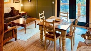 A cozy room with a wooden ceiling, a dining table with chairs, a sofa, and a television mounted on the wall. - Cozy Ski Retreat with Moutain View/Ski In Property/Hot tub/5 mins to the Lifts (Fernie)