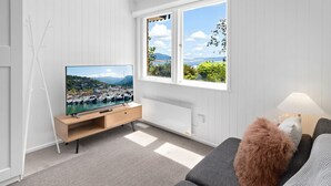 A modern living room with a television displaying a marina view, a sofa, and a lamp.