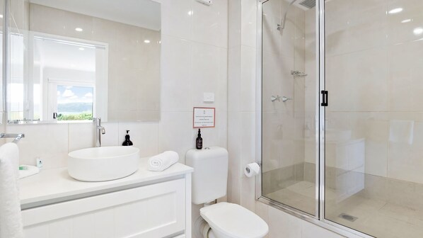 A modern bathroom with a large sink, toilet, and glass-enclosed shower.