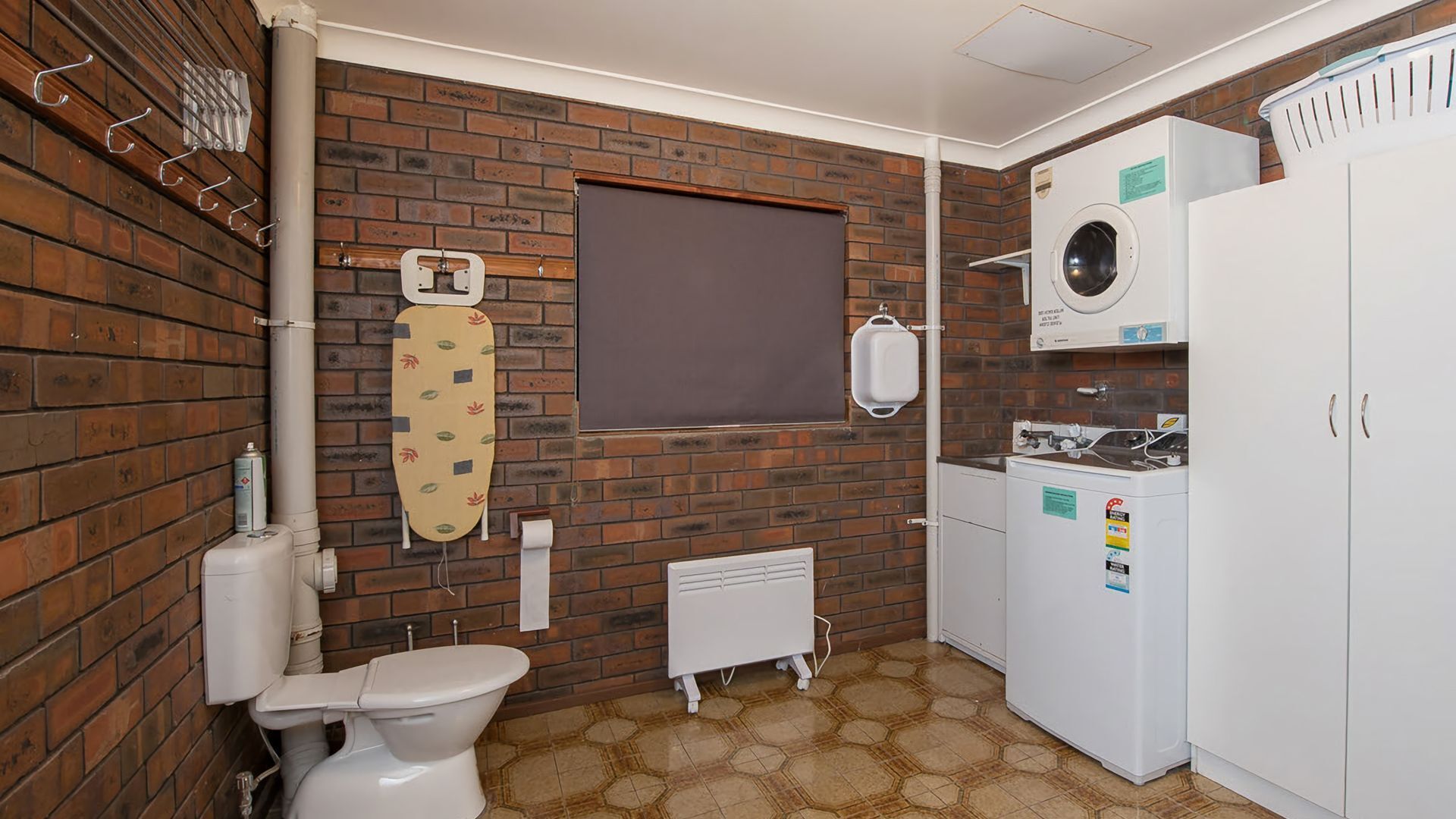 A compact bathroom with a toilet, a washing machine, and a radiator.