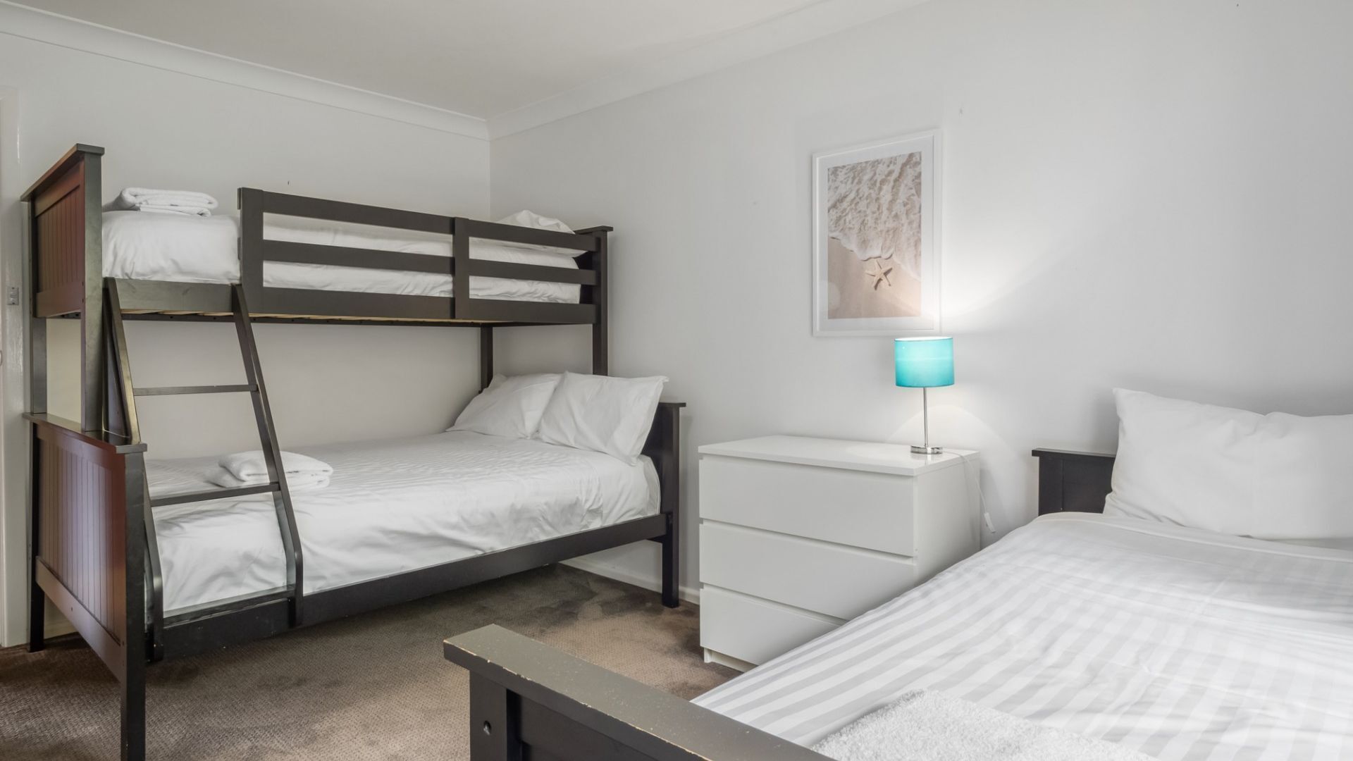 A bunk bed room with a desk and a lamp.