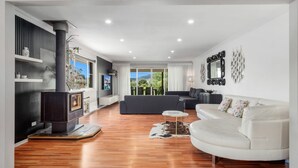 Un salon moderne avec une cheminée, un canapé et un divan blanc, ainsi qu’un téléviseur.