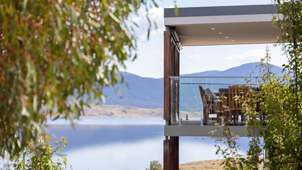 A modern outdoor seating area with a view of a lake and mountains.