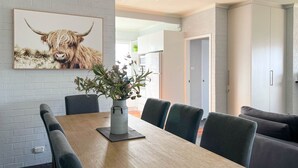 A dining area with a wooden table, grey upholstered chairs, and a potted plant.