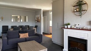 A modern living room with a grey sofa, a wooden coffee table, and a fireplace with a white mantel.