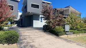 A modern residential building with a driveway leading to the entrance.