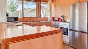 Una cocina moderna con una isla de madera, electrodomésticos de acero inoxidable y vistas al exterior.