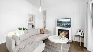 Un salon moderne avec un canapé, une cheminée, un téléviseur et une petite table sur laquelle est posé un vase.