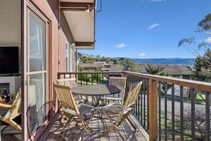 Un balcon avec une table et des chaises, un téléviseur et une vue sur le paysage.