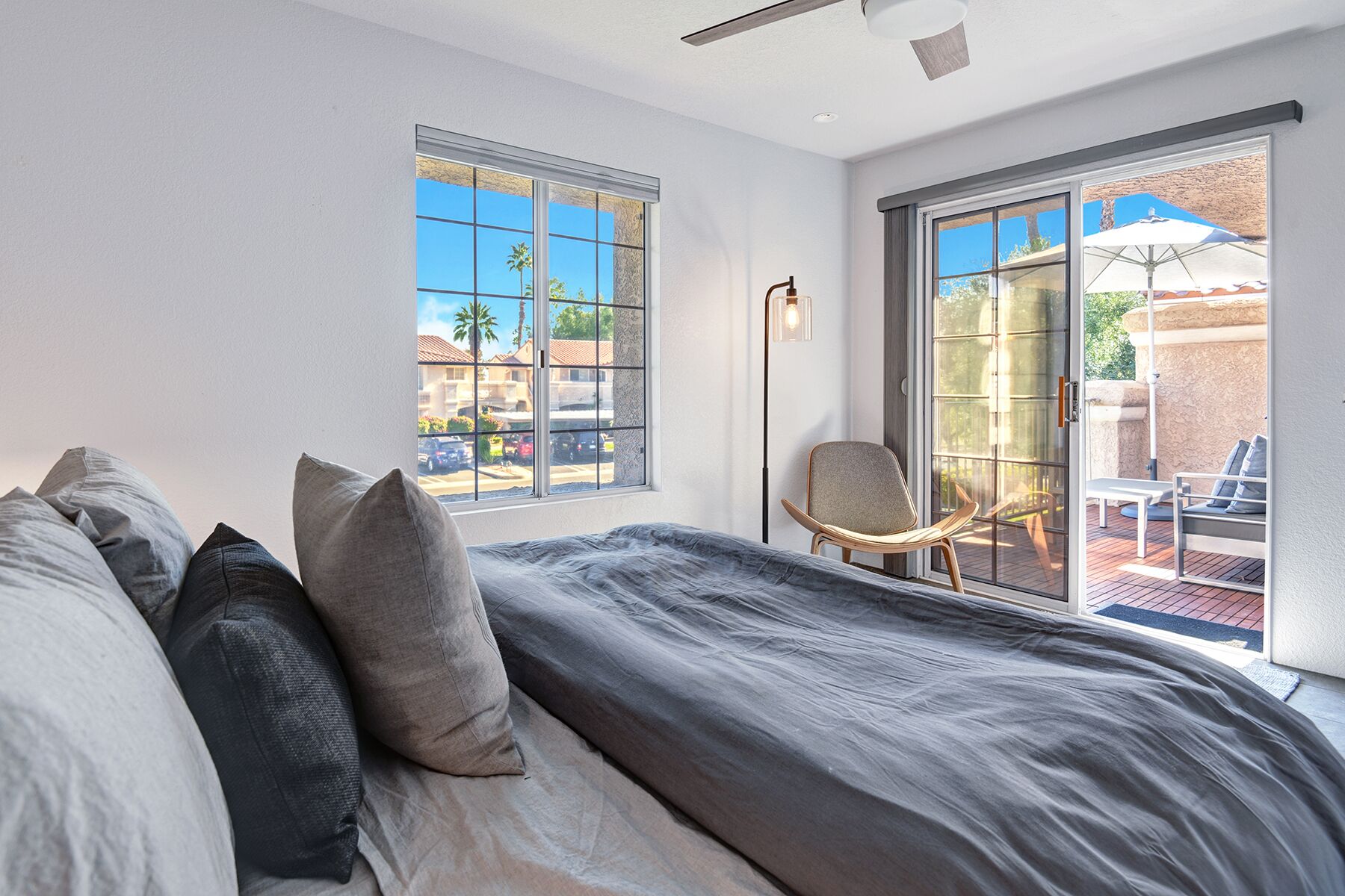 Un dormitorio con una cama grande, dos ventanas, una silla y vistas al exterior.