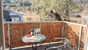 Ein Balkon mit einem Tisch für zwei Personen, einer Weinflasche und zwei Gläsern. Der Balkon hat eine dekorative Metallumzäunung mit kreisförmigen Mustern.