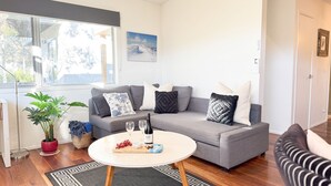 Ein modernes Wohnzimmer mit einem grauen Sofa, einem runden Couchtisch und einer Topfpflanze.