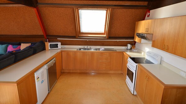 Une cuisine de taille réduite, dotée de meubles en bois, d’un four à micro-ondes, d’un évier et d’une cuisinière.