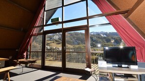 A room with a large window offering a mountain view, a television, and a small table.