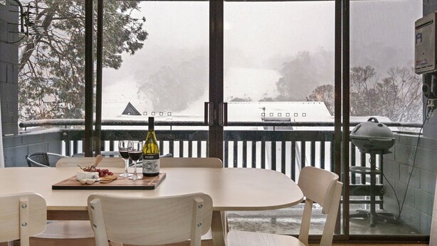 Comedor con mesa, sillas y vistas a un paisaje nevado a través de amplios ventanales.