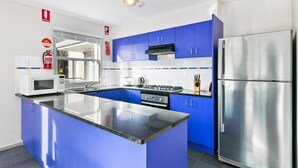 Une cuisine moderne avec des meubles bleus, des appareils en acier inoxydable et un îlot central.