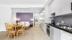 A modern kitchen with white cabinets, a Bosch dishwasher, and a dining area with wooden chairs and a table.