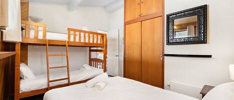Habitación con literas, un armario y un espejo.