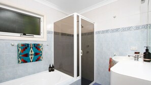 Ein Badezimmer mit Dusche, Waschbecken und Fenster.